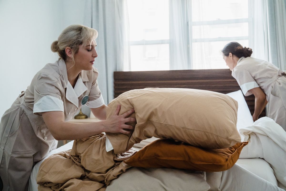 Housekeepers preparing a bright bedroom